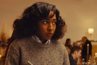 Opus (2025) Ayo Edebiri Looks around, nervously taking notes during a strange dinner party